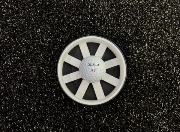 Titleist 99 golf ball centered on putting cup reducer demonstrating size comparison and target alignment for practice